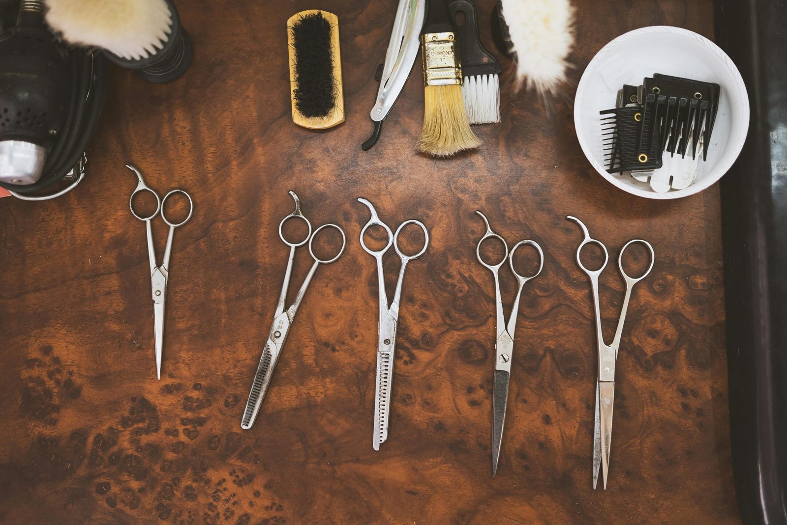 A collection of vintage barber tools including scissors and brushes on a wooden surface.